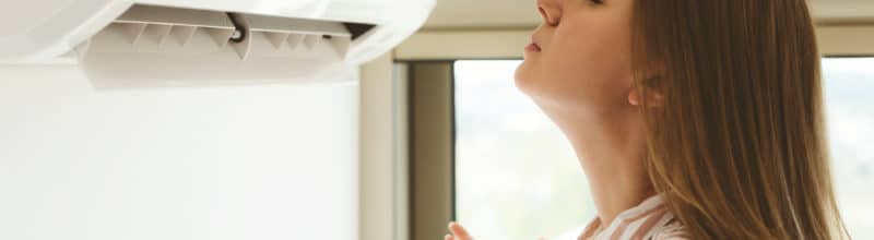woman holding her face up to a ductless ac unit