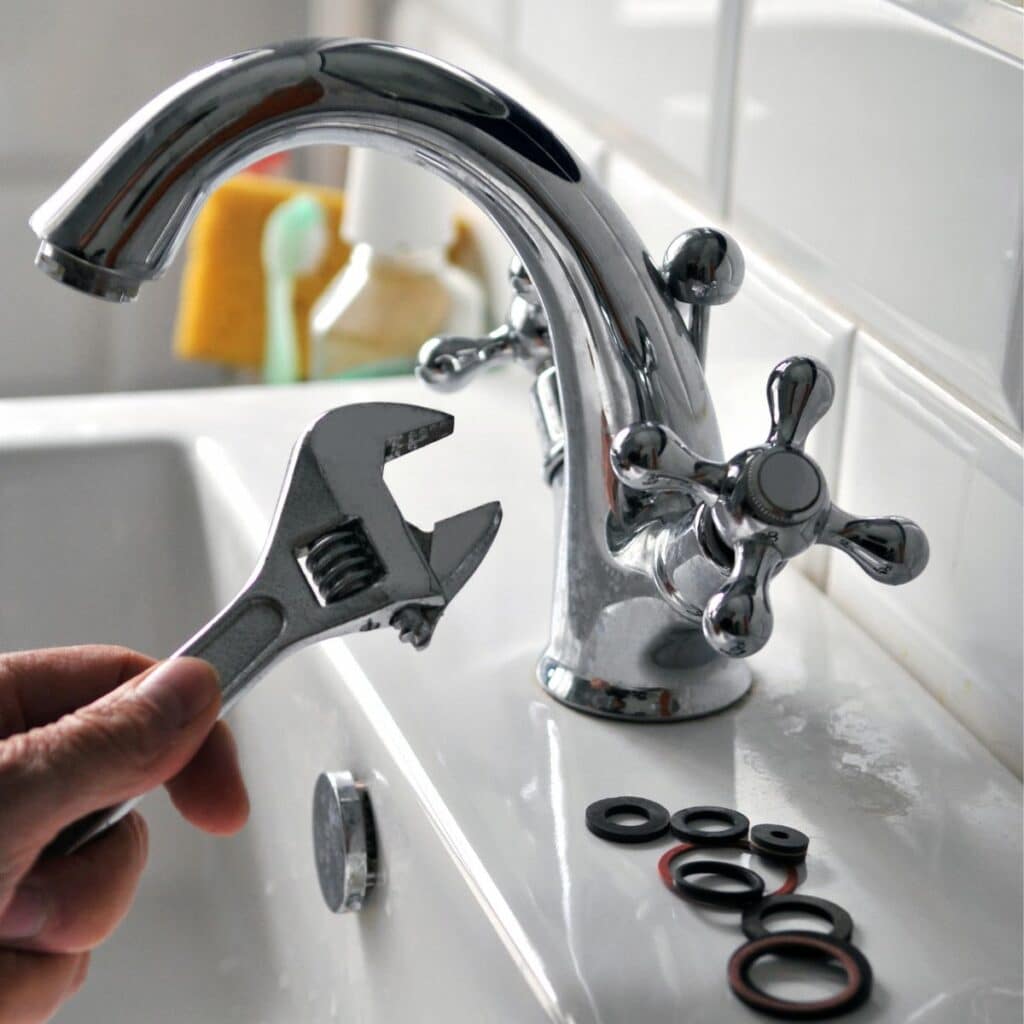 using a wrench to adjust a faucet