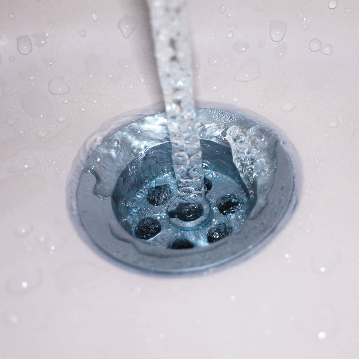 close up image of water stream going down the drain