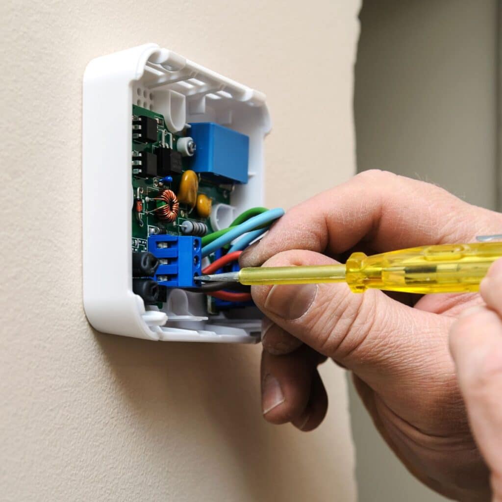 using a screwdriver to adjust a thermostats electronics
