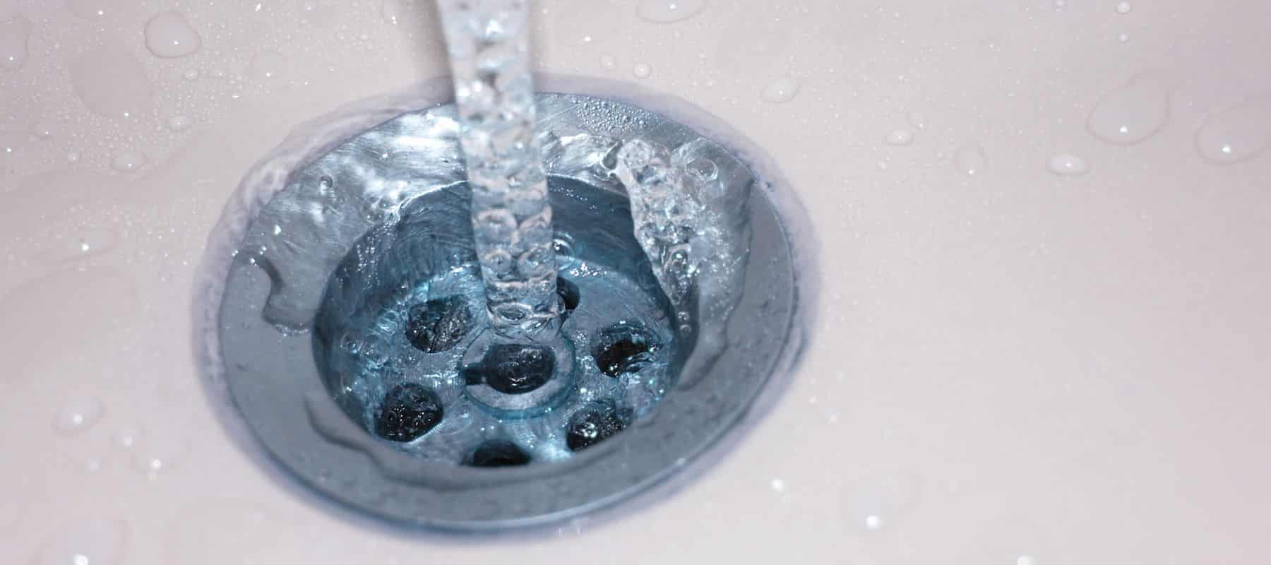 close up image of water stream going down the drain